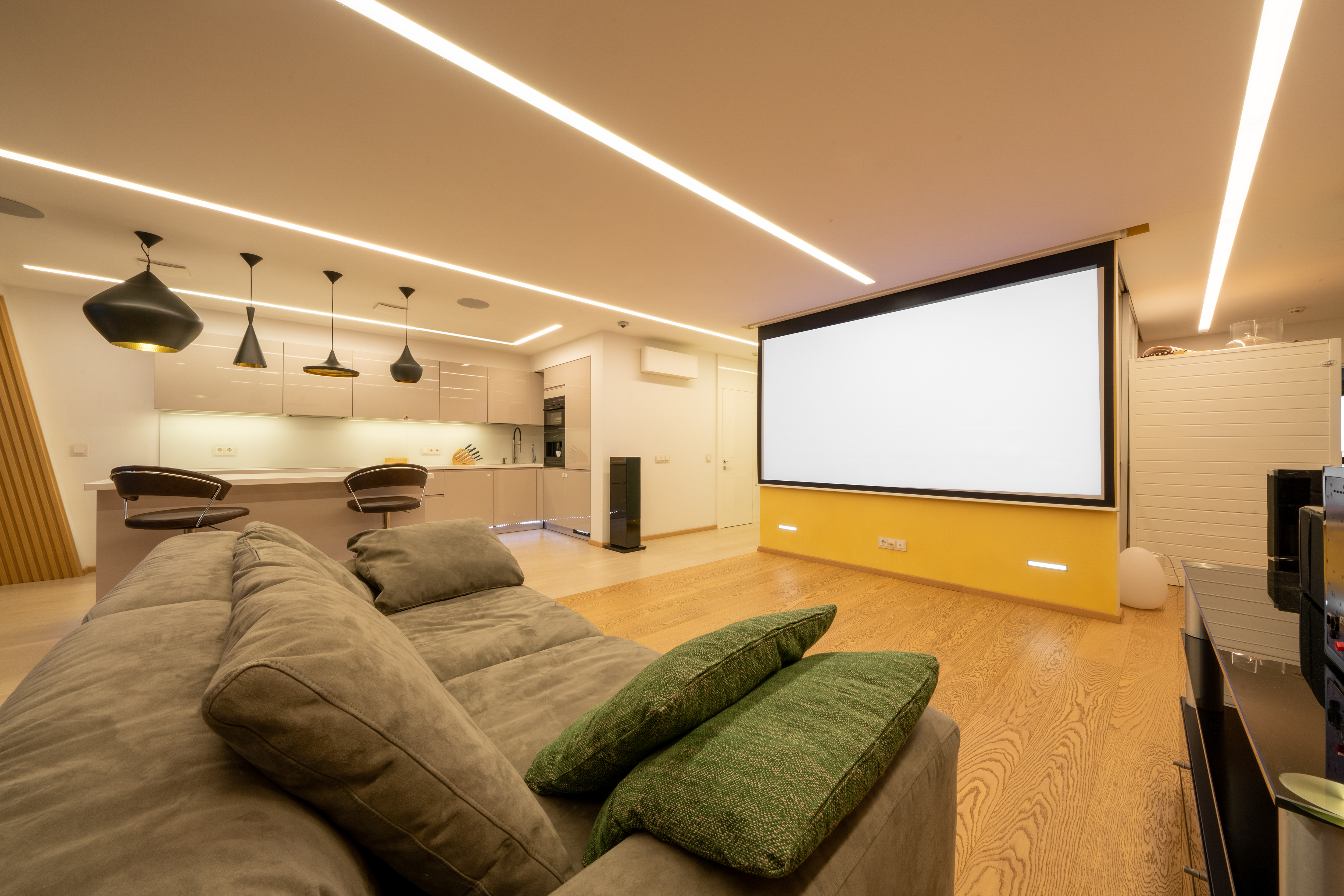 Finished basement with a home theater seating area and bar, moody warm lighting