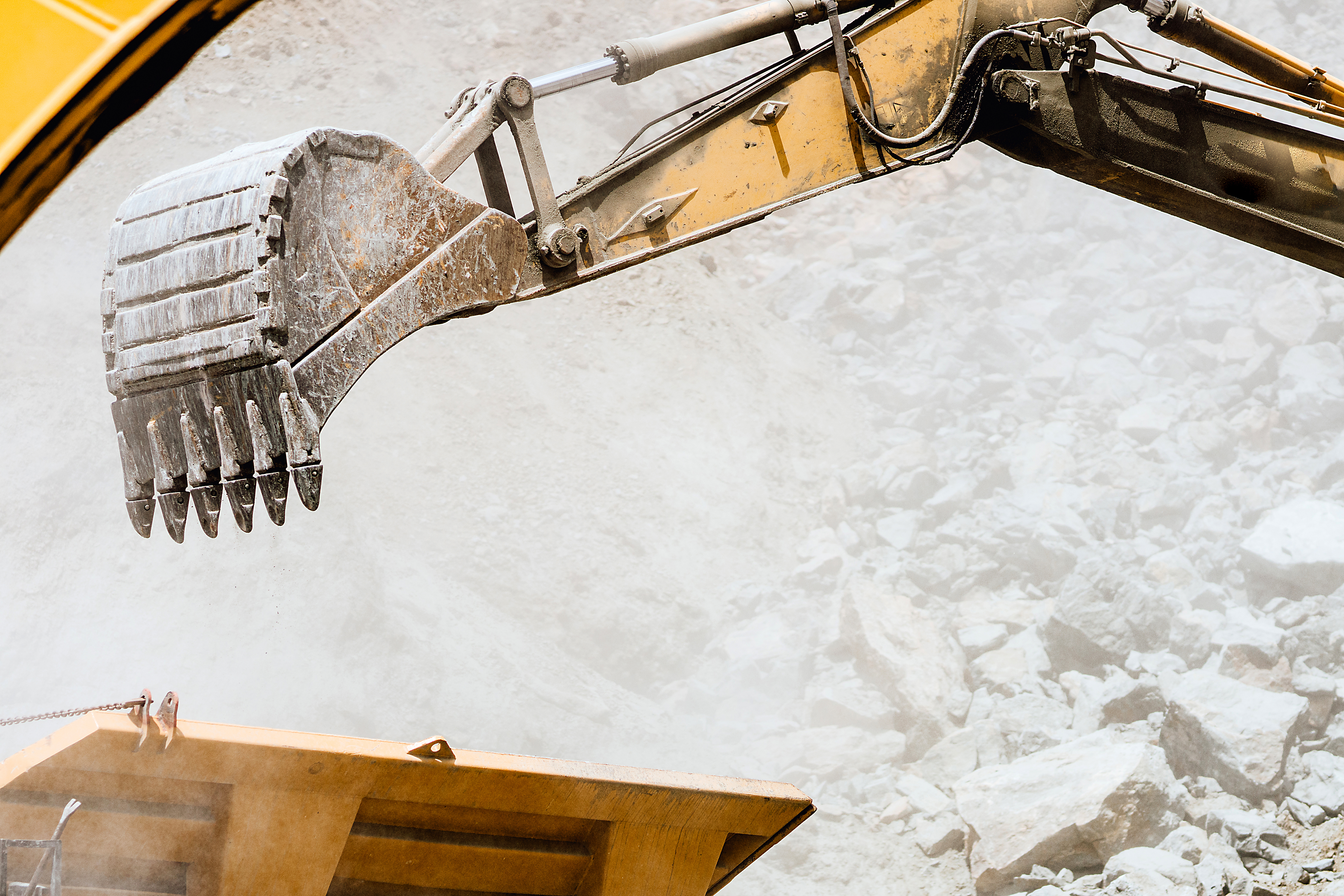 Excavator demolishing a commercial building, structure partially collapsed, dust