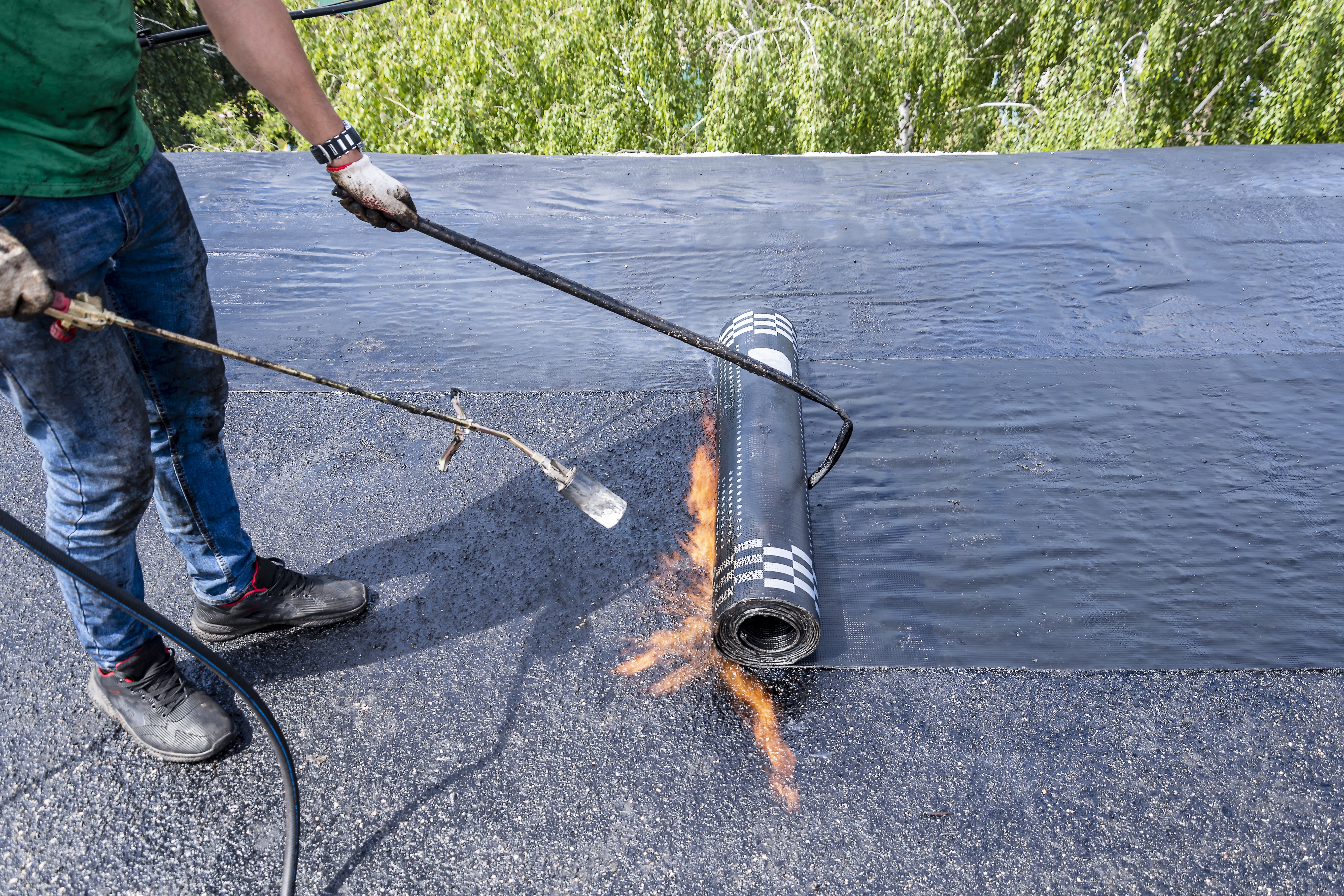 Roofing crew applying a silicone coating system to a large industrial roof